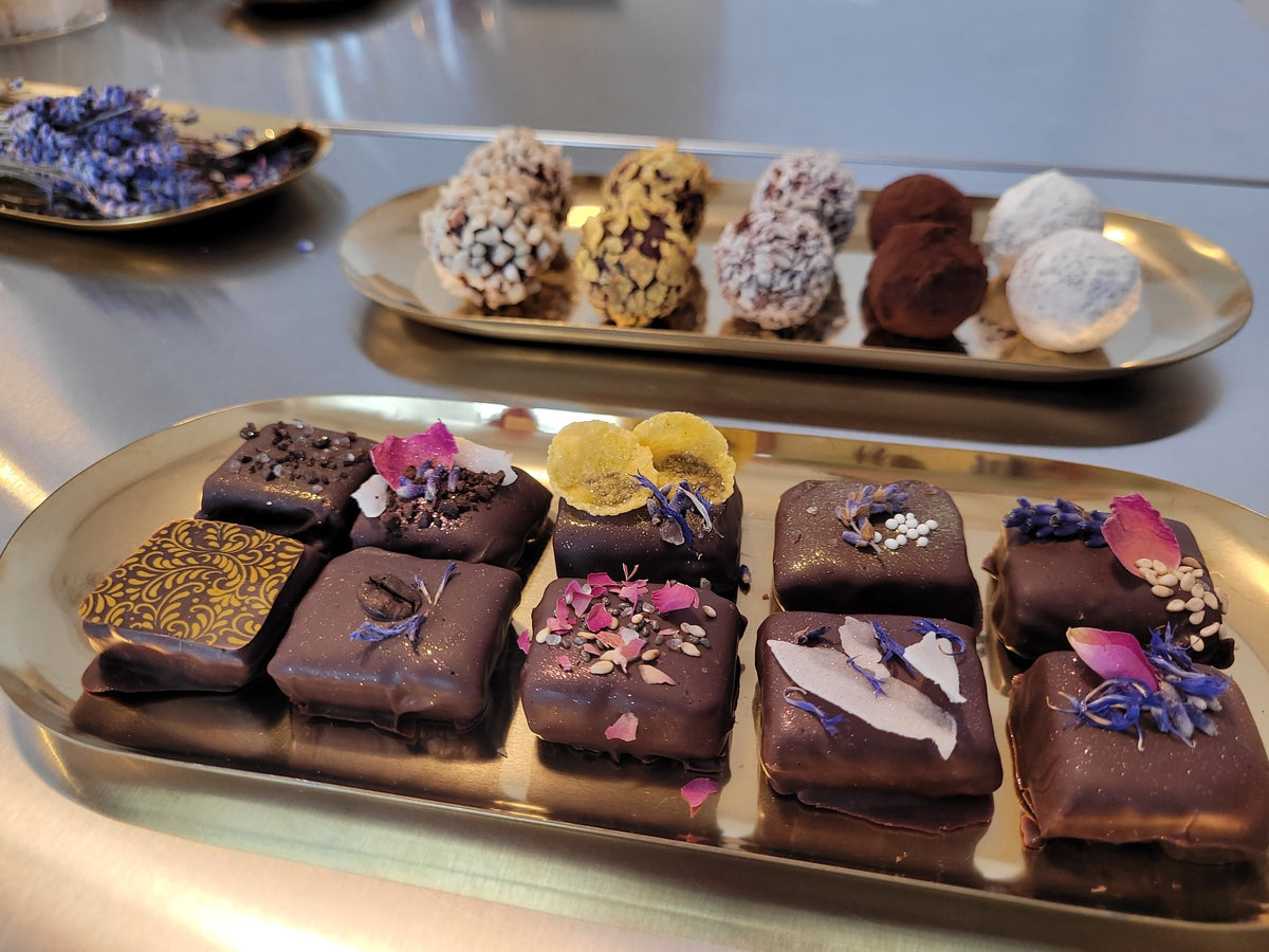 Selbstgemachte Pralinen mit Blütendeko und Trüffel auf Goldtabletts – Ergebnis im FERI Pralinenworkshop München