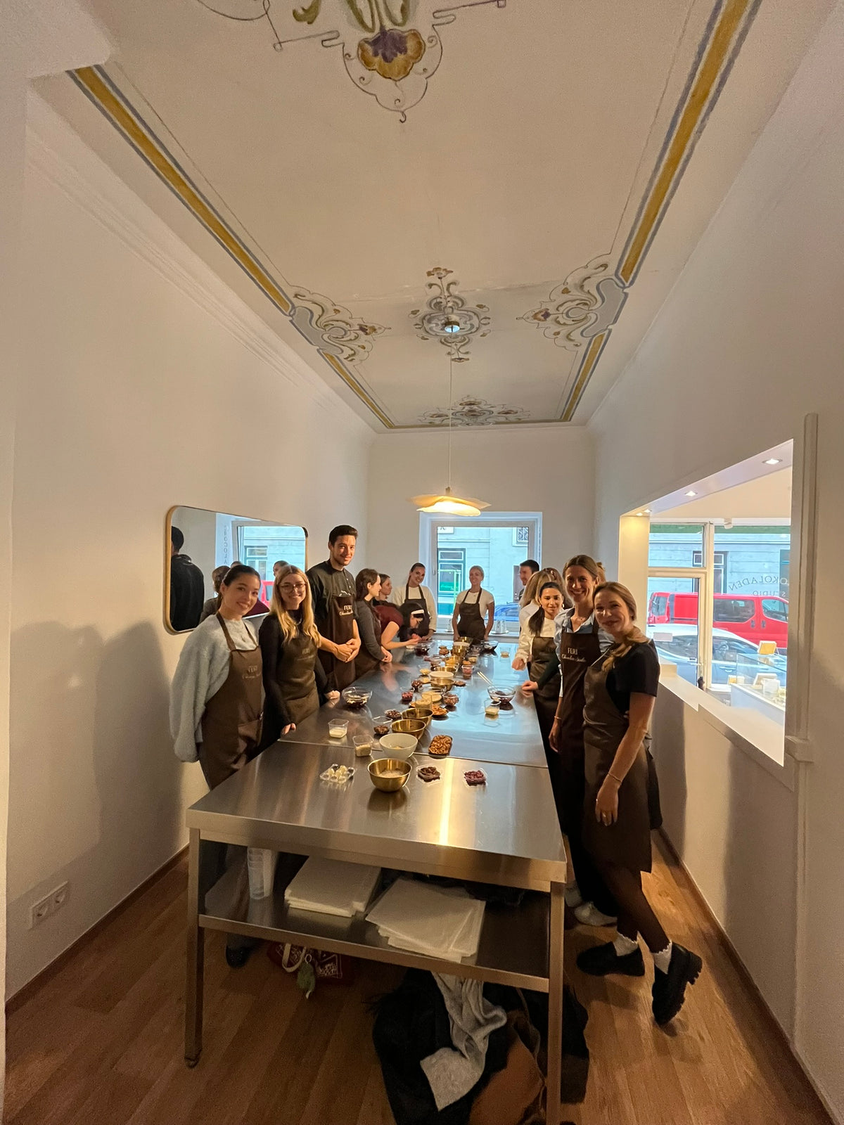 Firmen-Team in FERI-Schürzen versammelt um den Arbeitstisch beim Pralinenworkshop